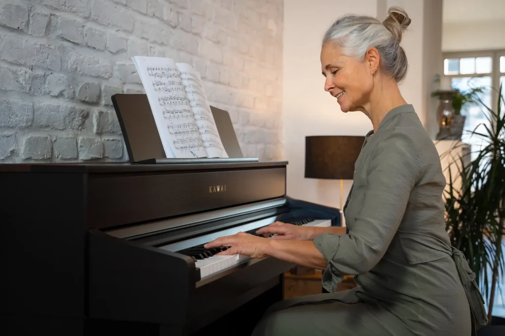A woman plays a black Kawai CA digital piano with sheet music.