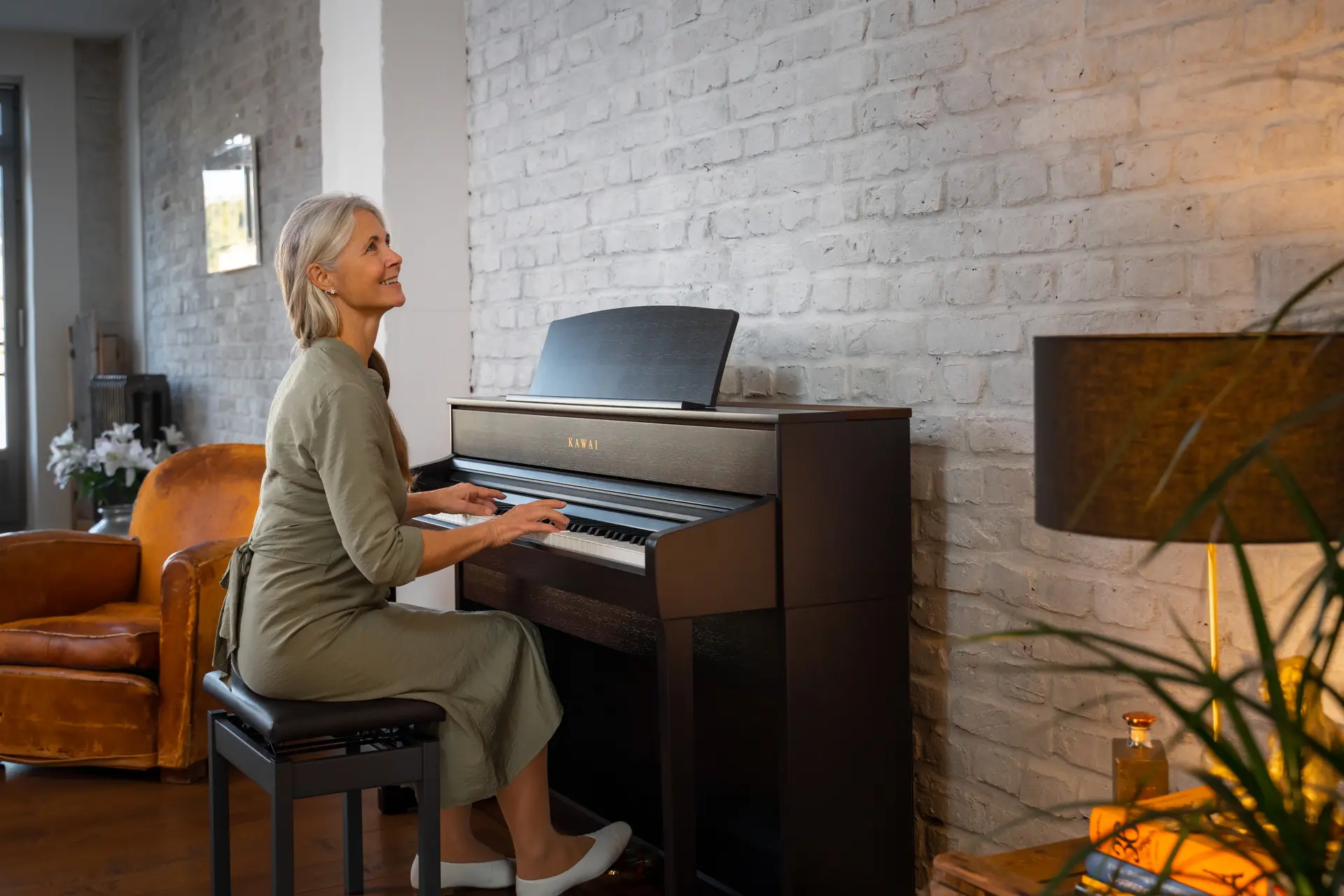 Woman playing a black Kawai CA digital piano in a living room.