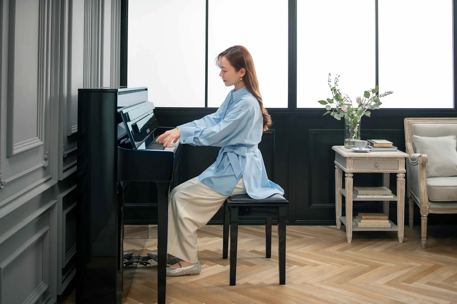 Femme jouant de côté sur un piano hybride Kawai NOVUS