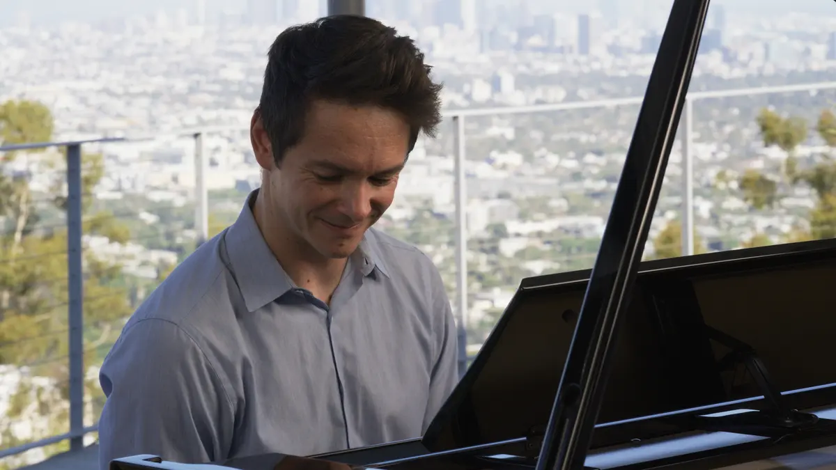 Pianiste sur le piano hybride Kawai NV12 devant une grande façade vitrée
