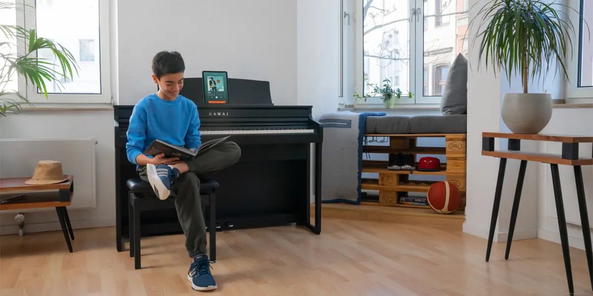 A person sits with a guitar next to a Kawai CA 401 digital piano