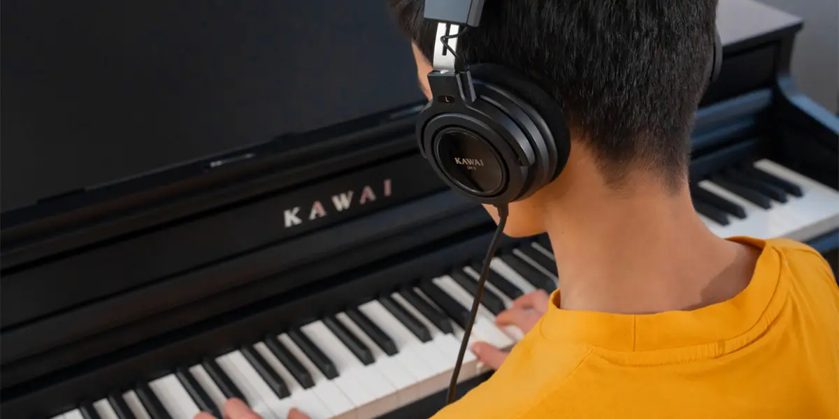 Person playing the Kawai CA 401 digital piano with headphones, rear view