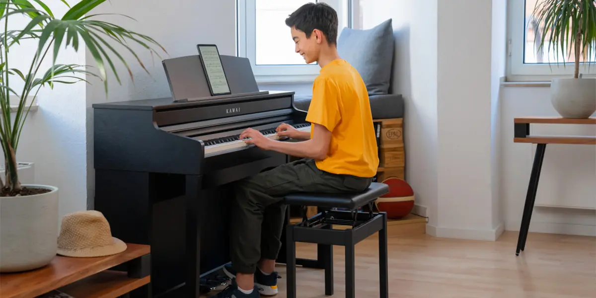 A person sits on the piano bench and plays the Kawai CA 401 digital piano