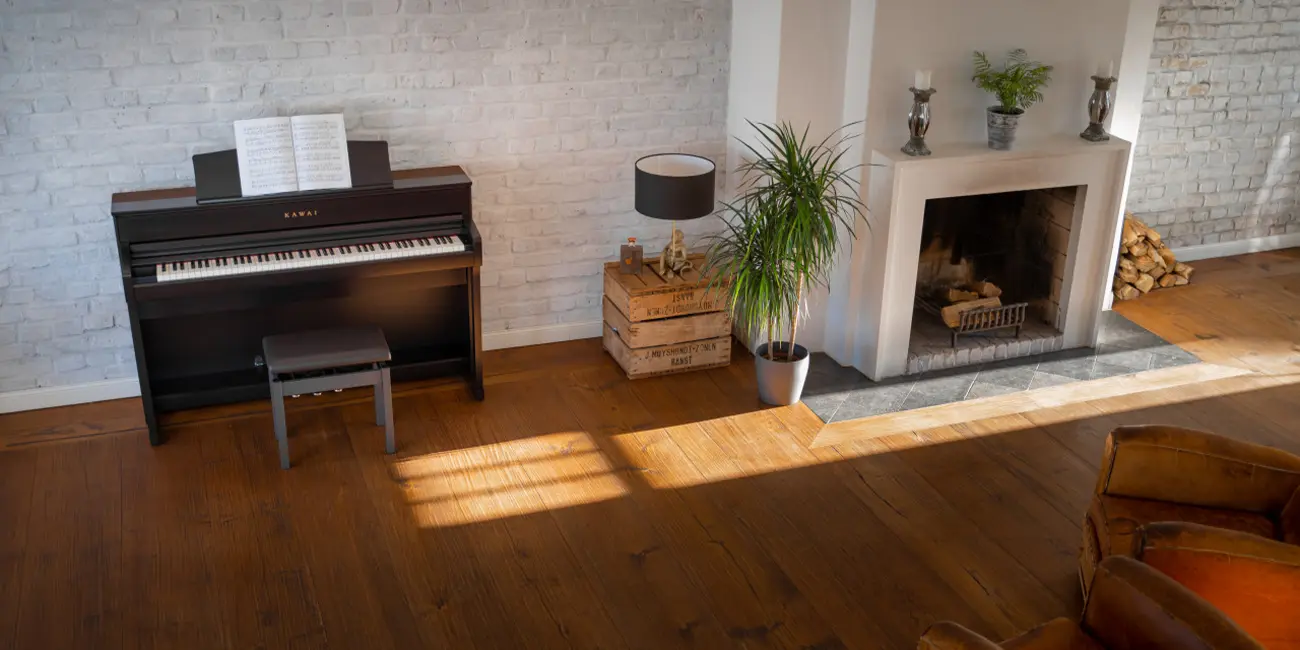 Kawai CA 701 digital piano with bench in front of a fireplace
