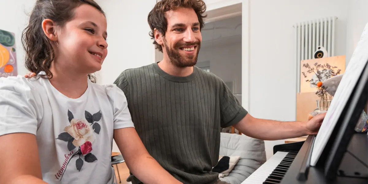 Mädchen spielt am Kawai CX202 Digitalpiano, ein Erwachsener begleitet sie