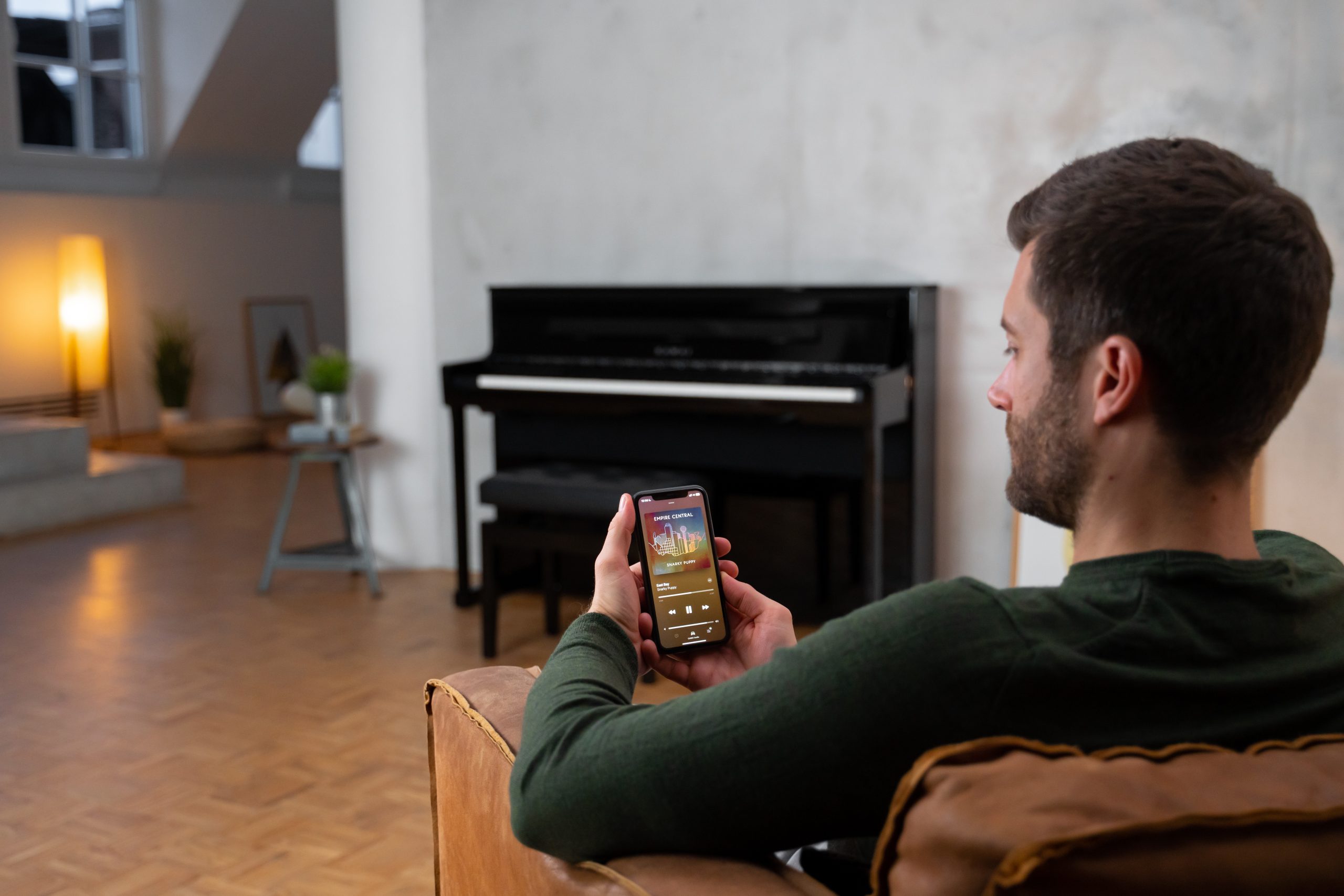 Mann im Wohnzimmer steuert das Kawai CA 901 vom Smartphone aus