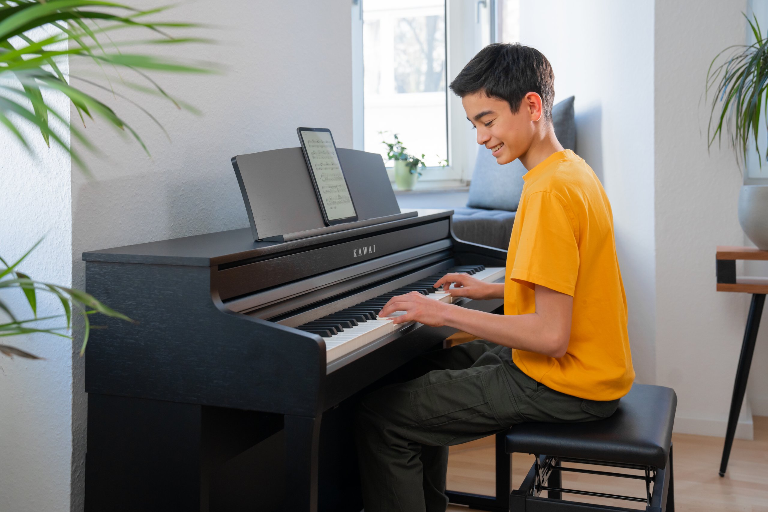 Ein junger Mann spielt das Kawai CA 401 in einem hellen Wohnzimmer