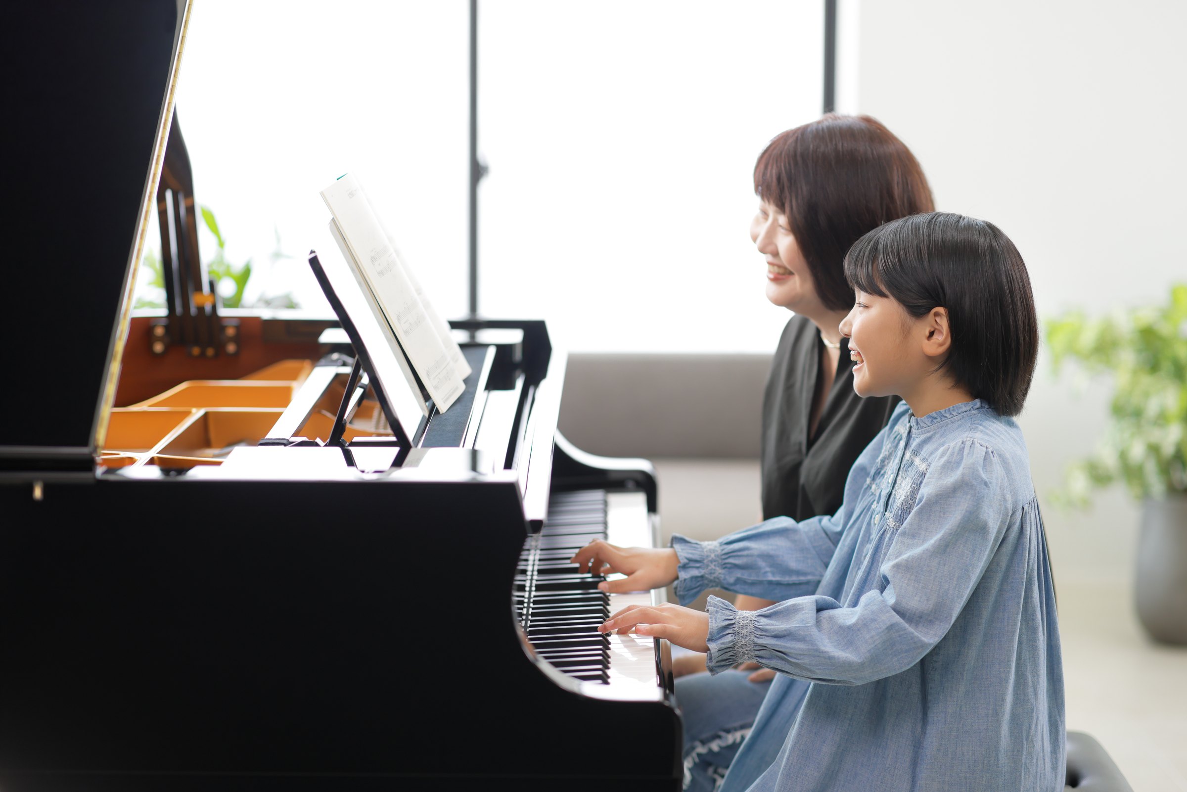 Zwei Menschen spielen an einem akustischen Kawai Flügel