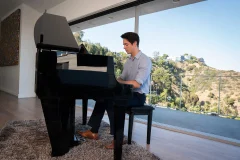 Le piano hybride Kawai NV6 joue devant une fenêtre panoramique