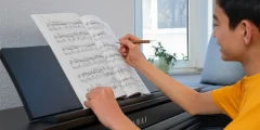 Person schreibt Notizen in ein Notenheft am Kawai CA 401 Digitalpiano
