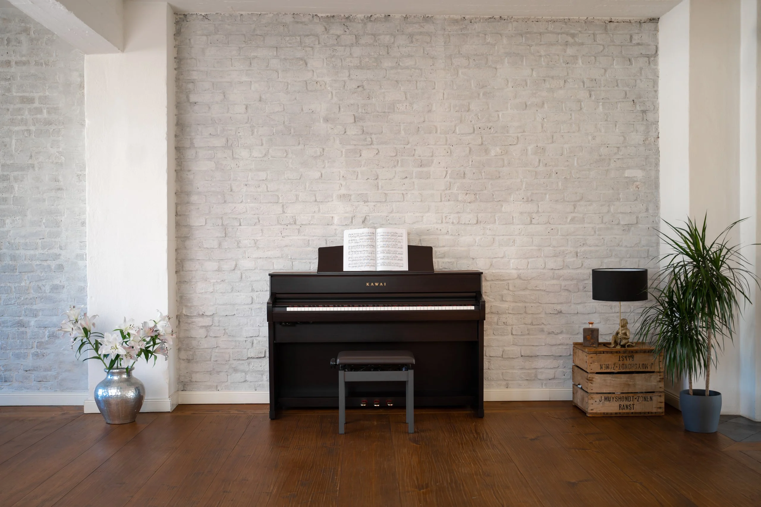 Kawai CA 701 digital piano in Premium Rosewood in a bright living room with a white brick wall