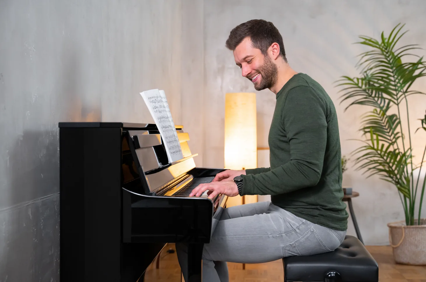 Lächelnde Pianistin spielt ein schwarzes Kawai CA Digitalpiano mit Noten auf dem Notenpult
