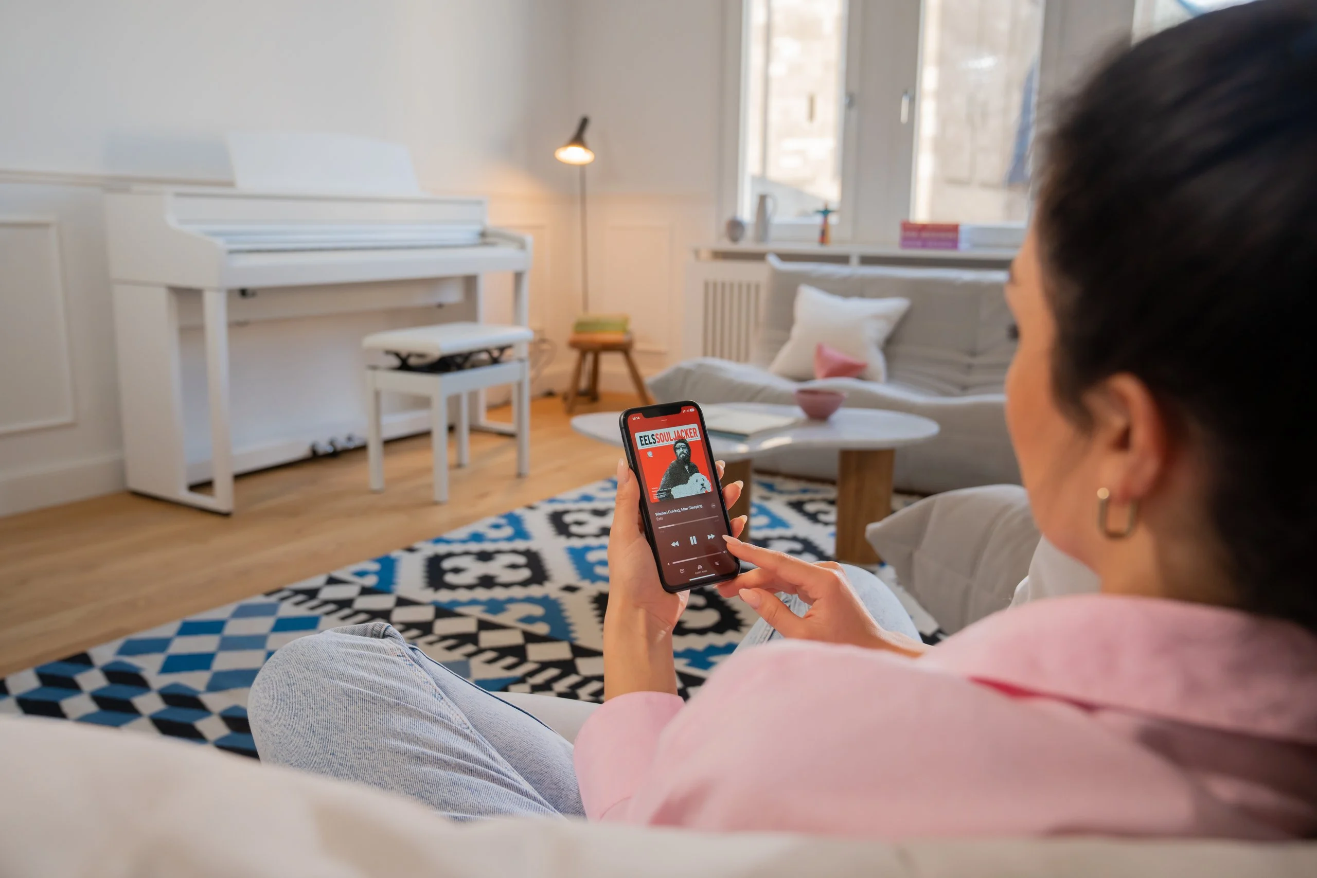 Frau auf dem Sofa steuert das Kawai CA 501 vom Smartphone aus