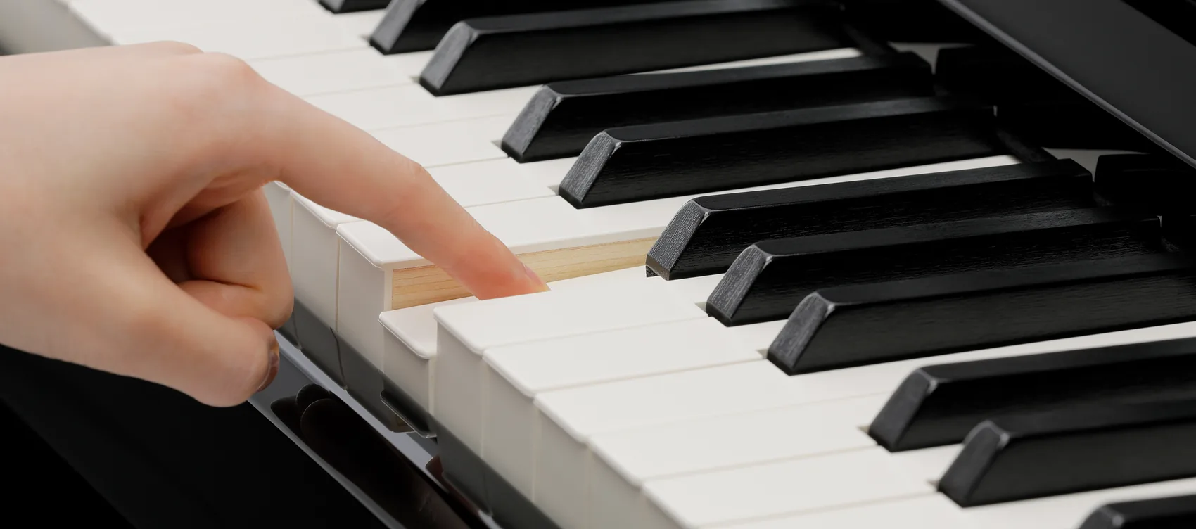 Finger auf einer Holztaste des Kawai Grand Feel Klaviaturmechanismus in Nahaufnahme