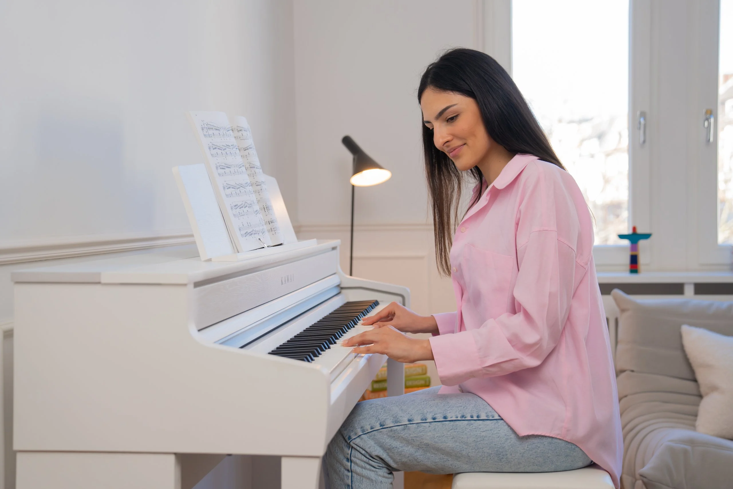 Eine Frau spielt das Kawai CA 501 in einem hellen Wohnzimmer