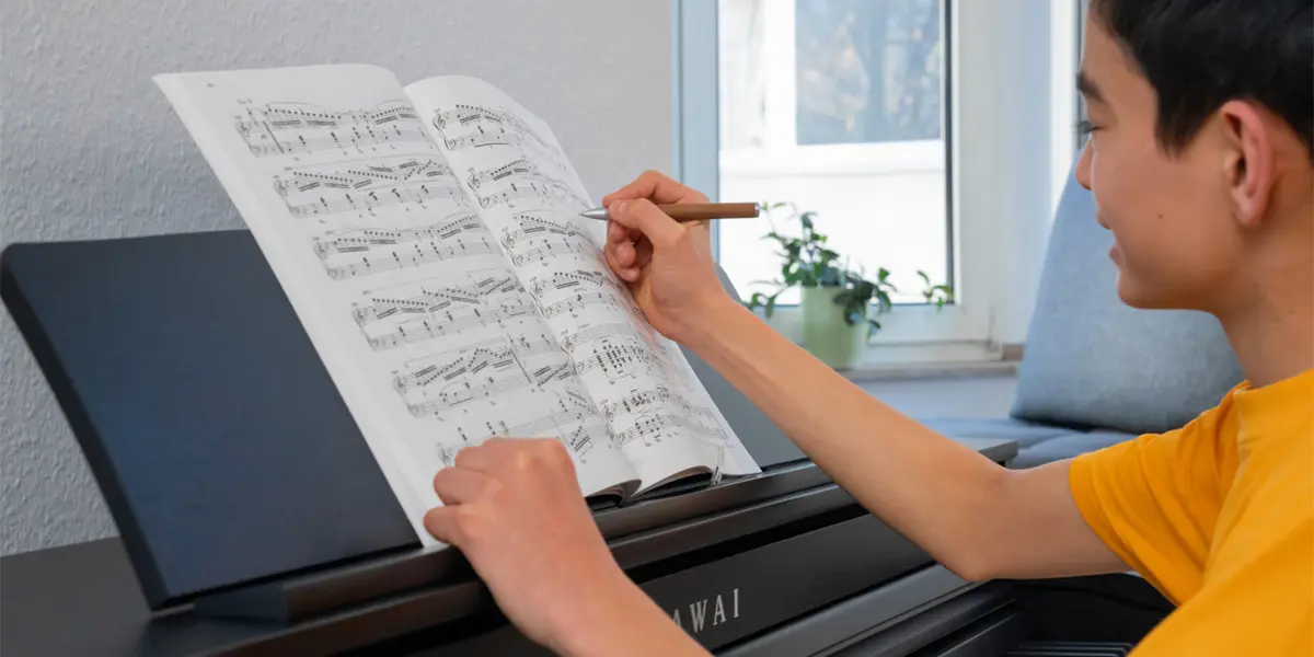 Person schreibt Notizen in ein Notenheft am Kawai CA 401 Digitalpiano